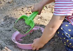 Kind spielt im Sand mit Schaufel