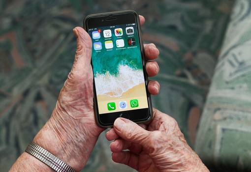 Faltige Hände halten Smartphone