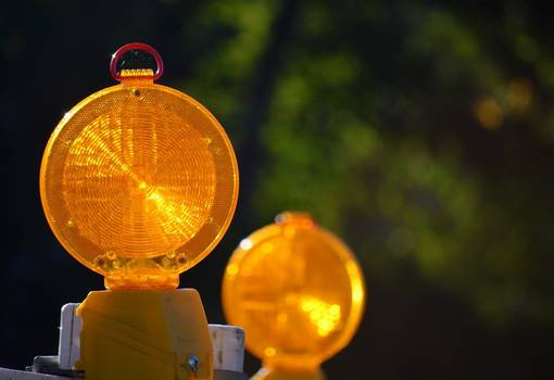 Zwei orang leuchtende Lampen einer Straßensperrung vor dunkelgrünem Hintergrund