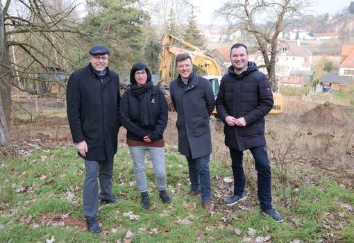 Fröhliche Menschen in Winterkleidung vor Baufeld im Grünen