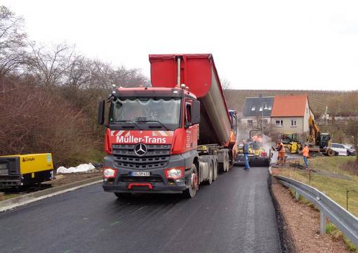 Großer Kipper lädt Baumaterial für Straße ab