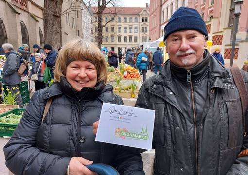 Frau und Mann Mitte 50 halten lächelnd einen Gutschein