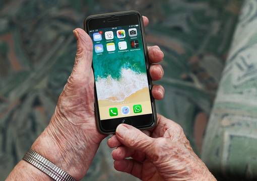 Faltige Hände halten Smartphone
