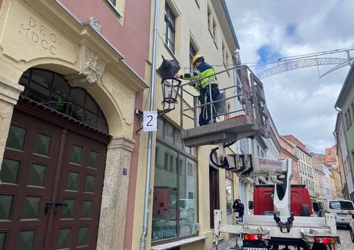 Arbeiter auf Hebebühne setzt LED-Leuchte in Laterne ein