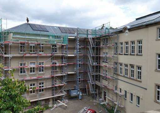 Schulgebäude mit Fassadengerüst und Solarplatten auf dem Dach