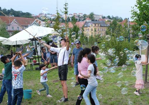 Kinder spielen mit Seifenblasen, die ein Künstler pustet