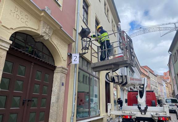 Arbeiter auf Hebebühne setzt LED-Leuchte in Laterne ein