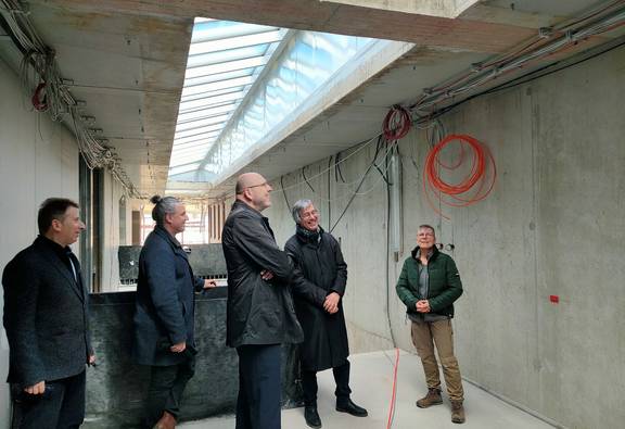 Personen im Gespräch in hellem, teilweise noch im Bau befindlichen Treppenaufgang mit Oberlichtern